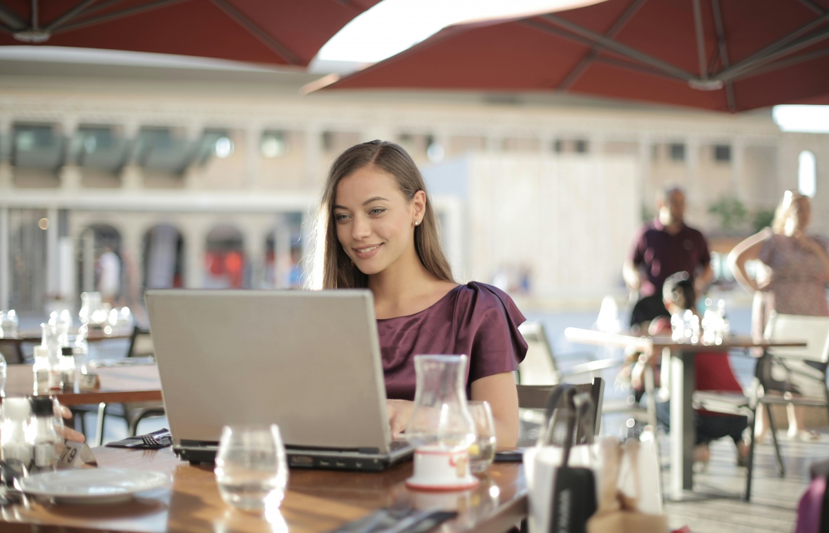 Vrouw werkt op horeca terras op laptop